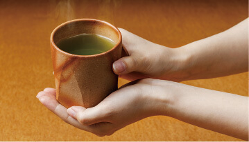 備前焼のコップに温かいお茶を注いだのイメージ